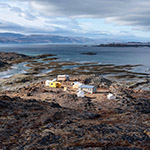 Un ensemble de cabanes et de tentes situées sur une formation rocheuse le long de la côte de l'océan Arctique.