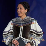 La maîtresse de cérémonie, Miali Coley-Sudlovenick, debout sur scène, en tenue traditionnelle.