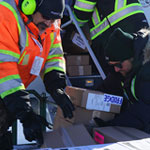 Three Harvest Manitoba  workers loading a plane with food.