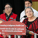 Un groupe de personnes sur scène annonce son soutien à l'amélioration des soins de santé dirigés par les Autochtones pour les communautés des Premières Nations.
