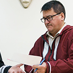 Quatre (4) personnes sont assises à une table pour signer le premier accord de coordination inuit.