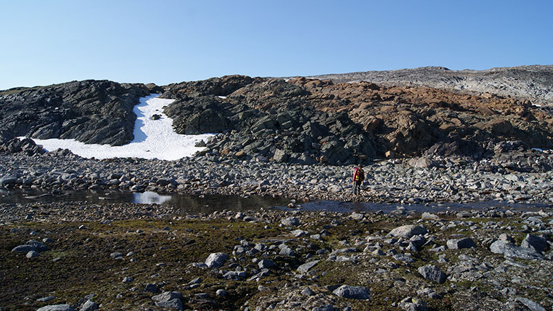 Un homme debout devant un ruisseau sur un flanc de montagne